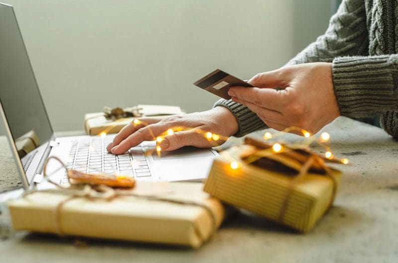 a man using a laptop with christmas gifts