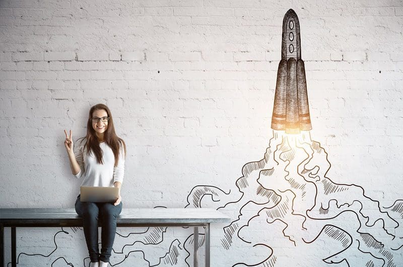 5-Ways-to-Get-Your-Industry-to-Sit-Up-and-Take-Notice a woman sitting at a table with a laptop and a rocket