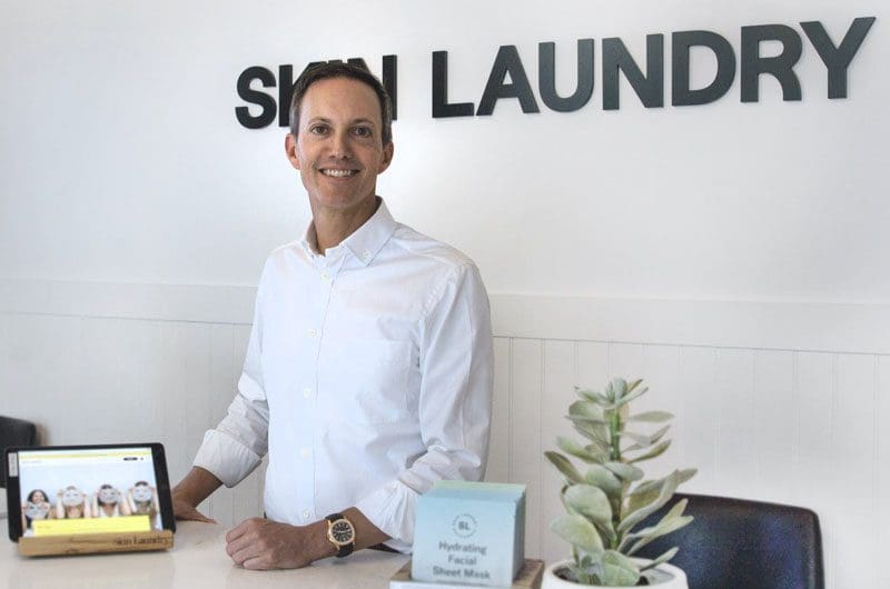 stop-waiting-for-a-big-idea-success-is-all-about-this-one-thing-says-this-health-and-wellness-leader a man standing in front of a sign that says shin laundry