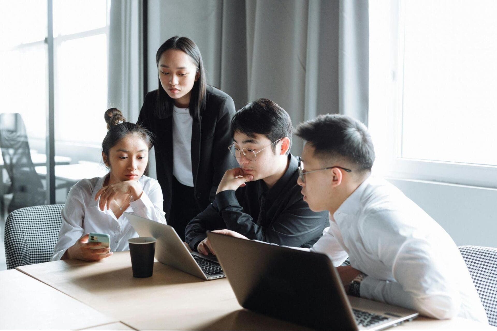 Four professionals looking at their laptop screens and discussing their 2026 plans.