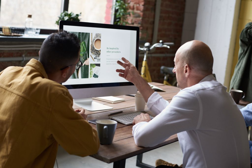 Two digital marketing consultants analyzing a contractor website design and local seo metrics on a desktop computer monitor.